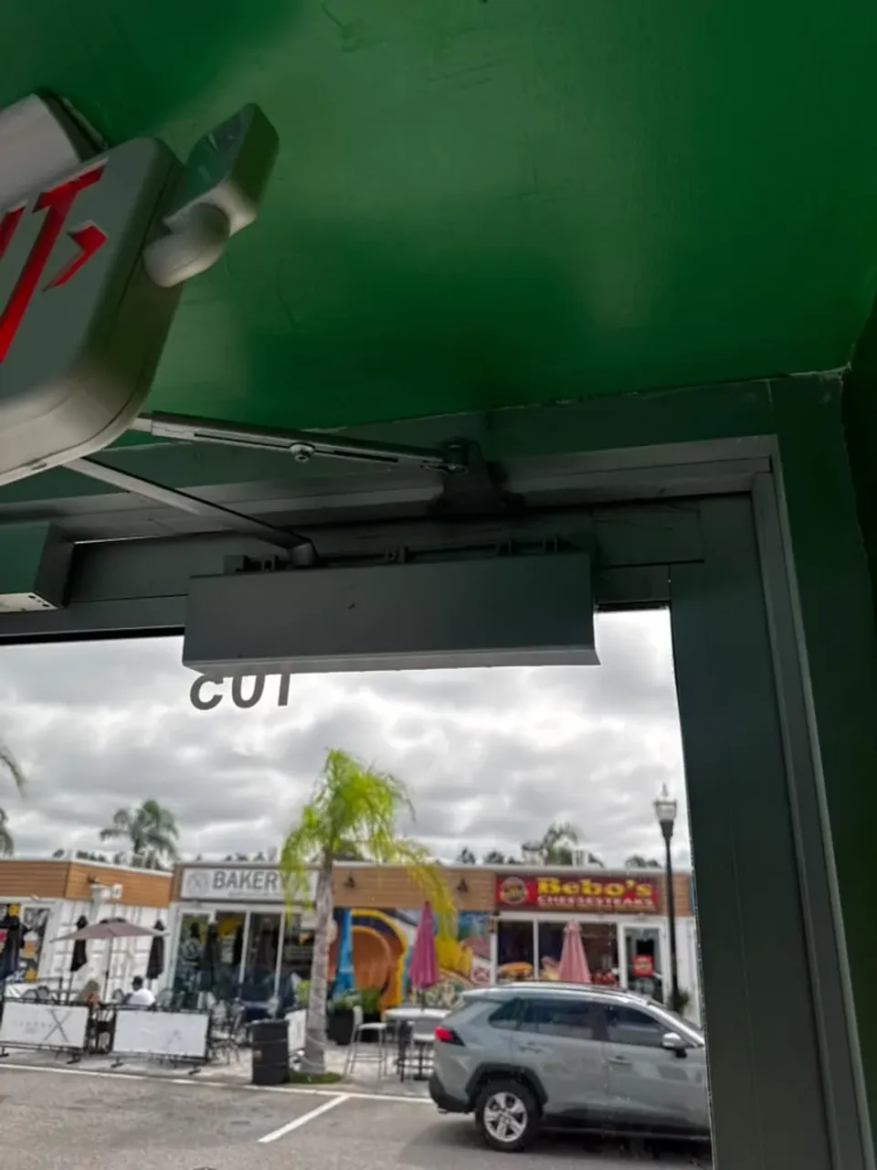 Surface-mounted commercial door closer and its arm above a glass door