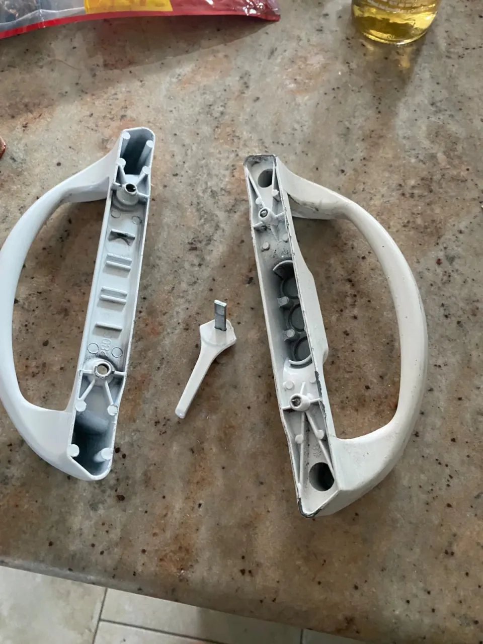 Removed sliding-door handle halves and a separate thumbturn on a work surface