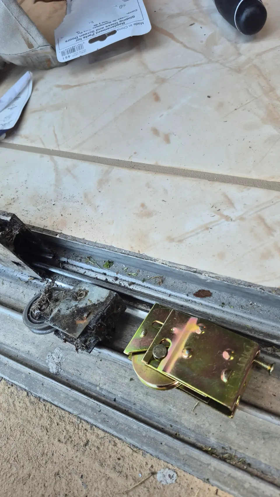 Worn sliding-door roller assembly beside a replacement roller