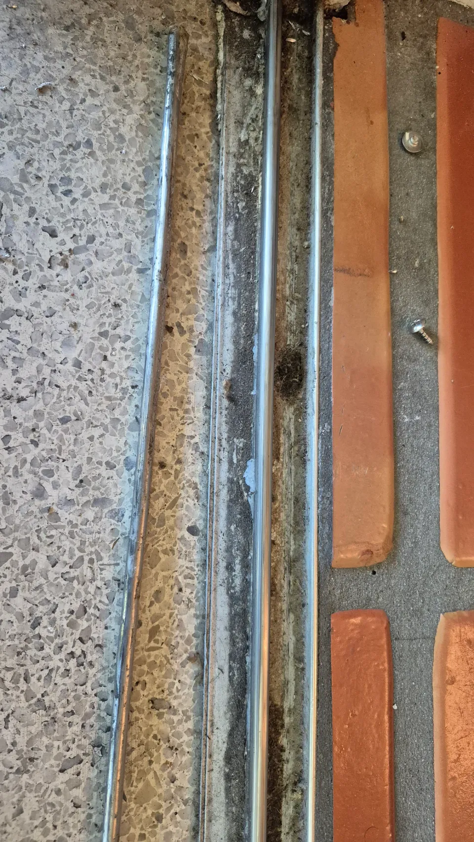 Close-up of a sliding-door track with a separate metal repair strip beside it