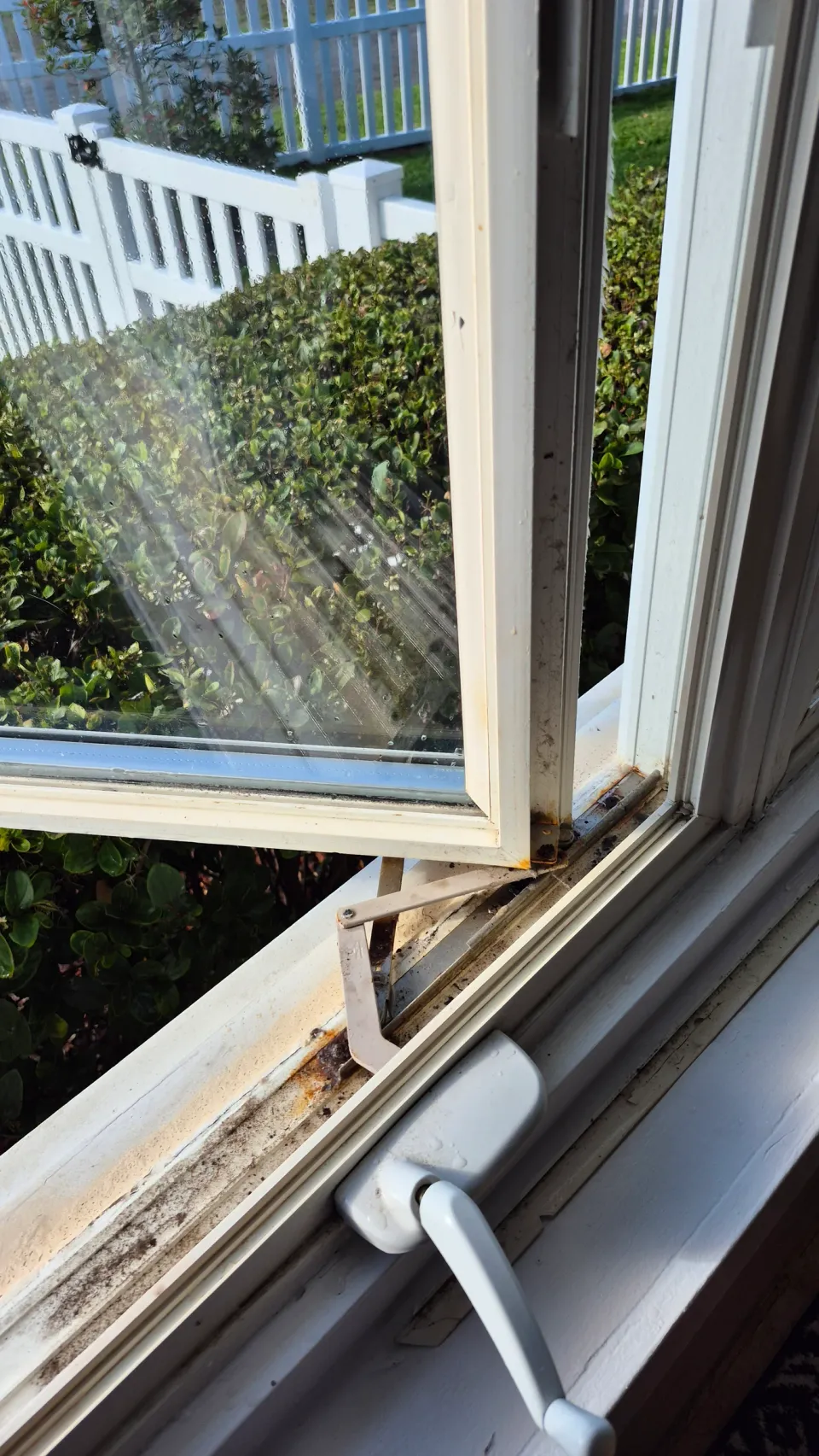 Open casement window showing its crank handle and operating arm